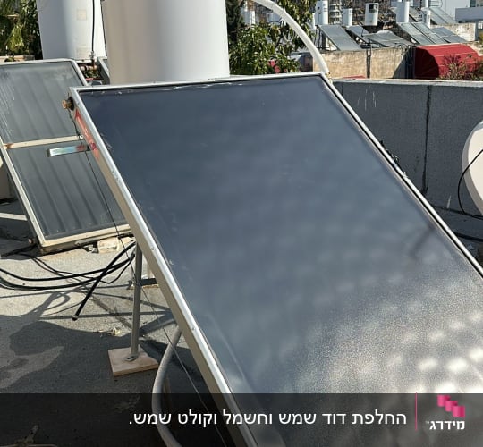 דוד שמש וקולטים על גג עם בניינים ברקע